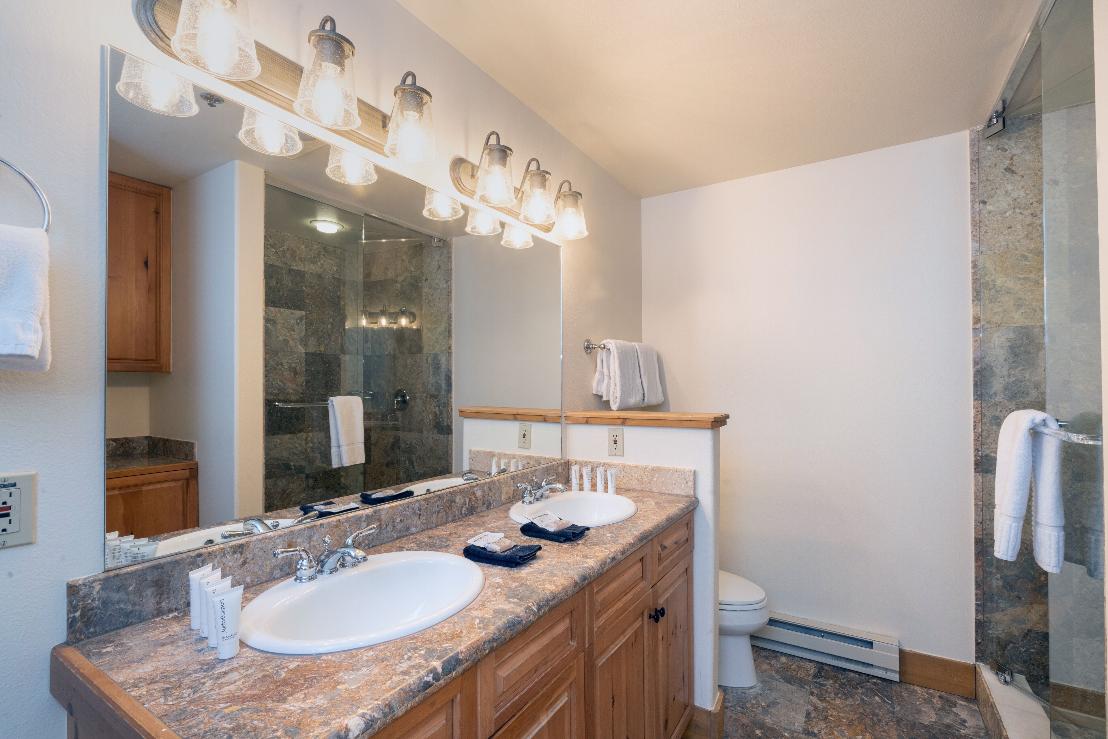 A bathroom with two sinks, a large mirror, and a shower area.