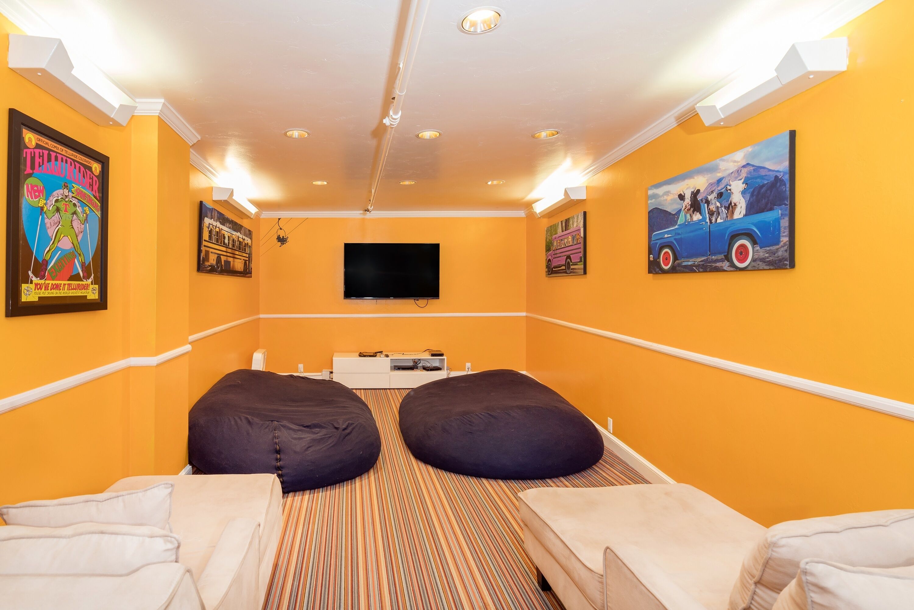 A room with two beds, a flat-screen TV, and artwork on the walls.