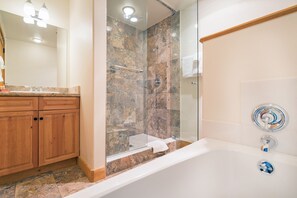Bathroom features a glass-enclosed shower, bathtub, and wooden vanity with a mirror.