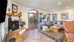 A spacious living room with a fireplace, comfortable seating, and large windows. - Bear Creek Lodge 212 3 Bedroom Condo by Alpine Lodging Telluride (Telluride)