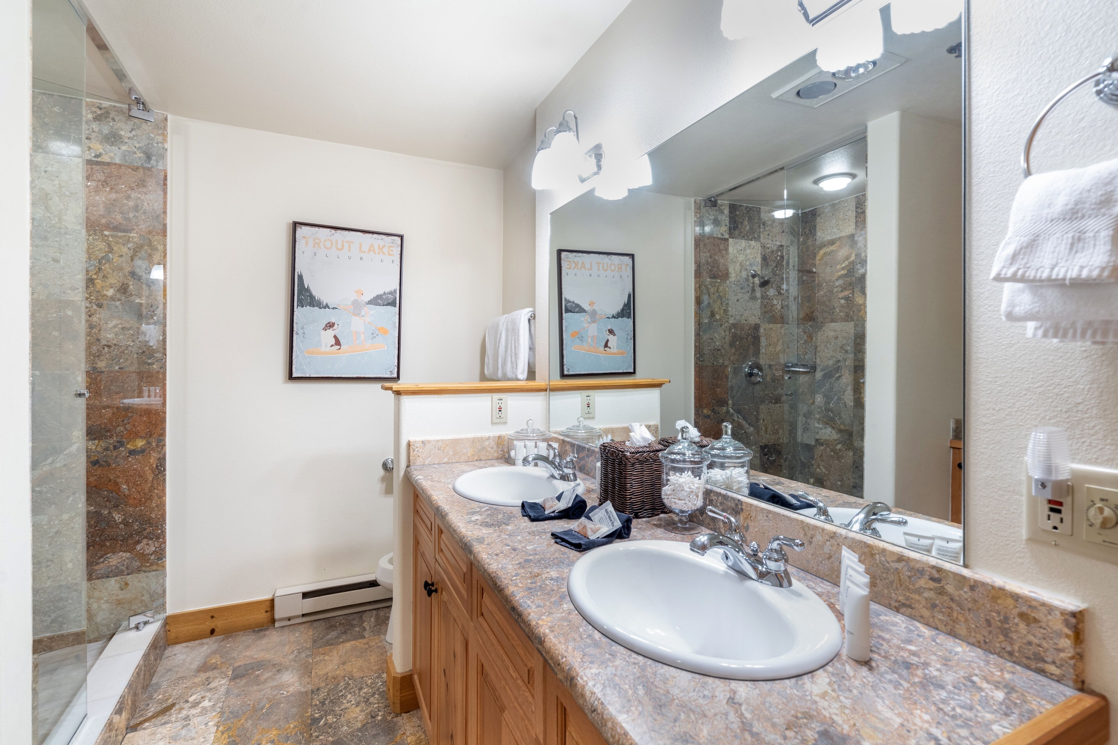 A modern bathroom with two sinks, a large mirror, and a shower area.
