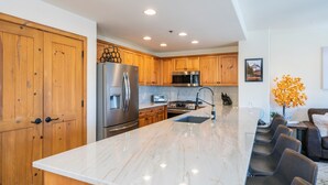 A modern kitchen with wooden cabinets, stainless steel appliances, and a marble countertop. - Bear Creek Lodge 309a 1 Bedroom Condo by Alpine Lodging Telluride (Telluride)
