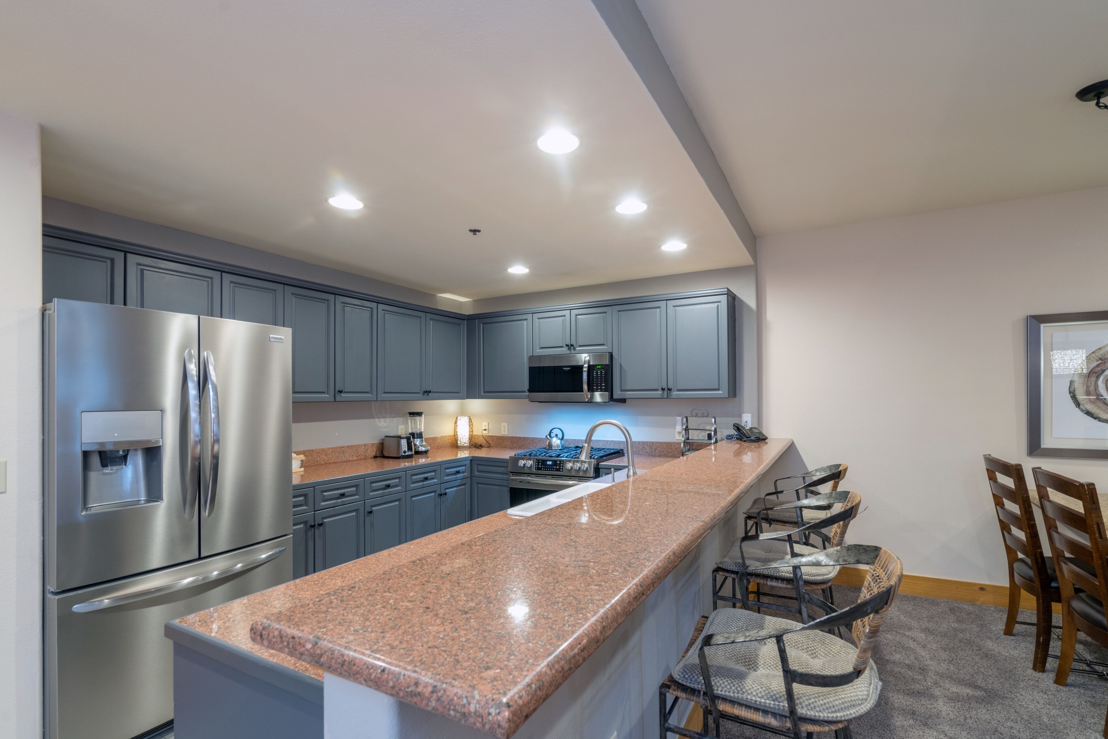Una cocina moderna con encimeras de granito, electrodomésticos de acero inoxidable y una barra de desayuno.