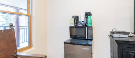 A compact kitchenette with a microwave, coffee maker, and a small refrigerator.