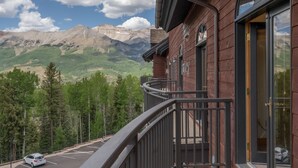 A hotel with a mountain view, a parking lot, and a balcony with a railing.