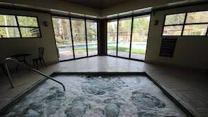 A spa area with a hot tub, large windows, and a view of a pool and garden. - 1952 Northstar 3 Bedroom Townhouse by RedAwning (Keystone)