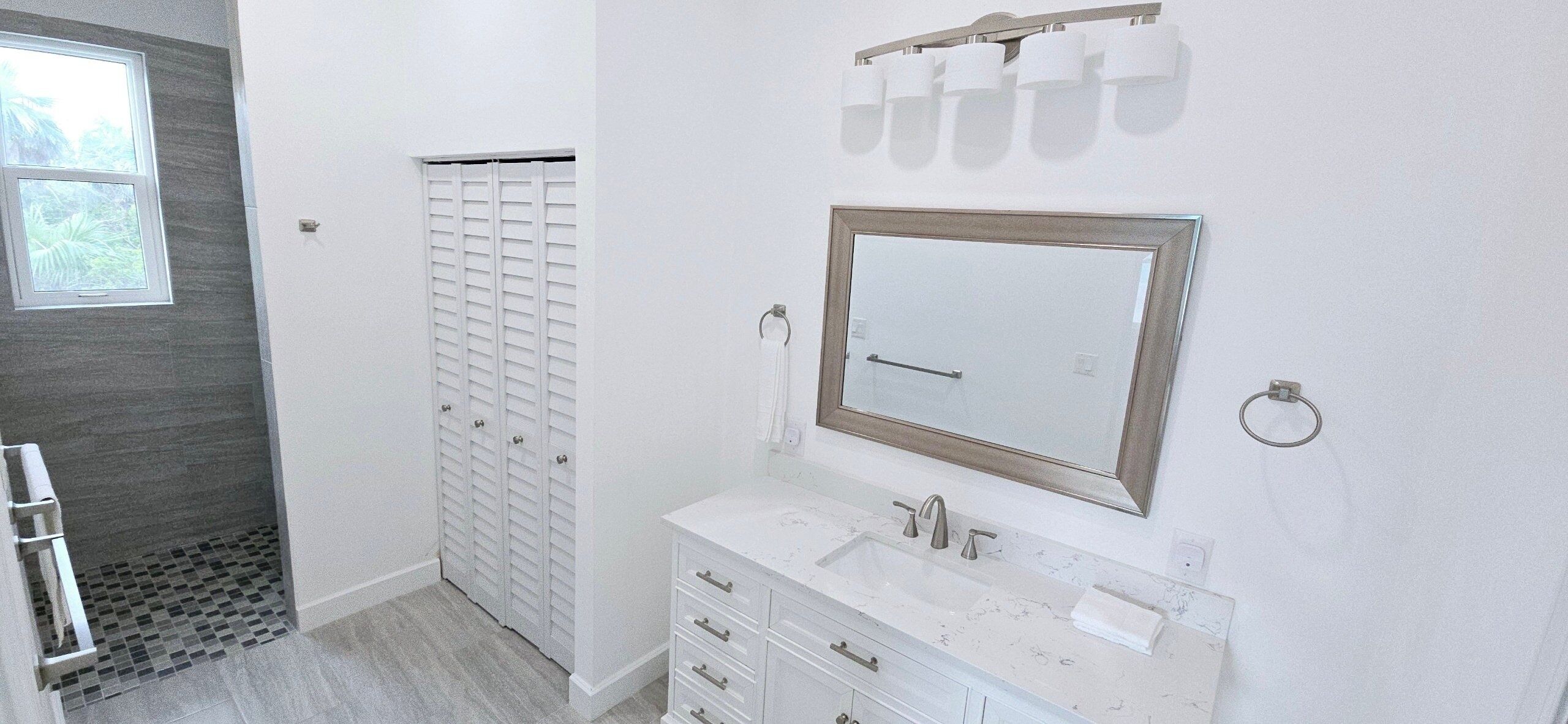 Une salle de bain avec un meuble-lavabo blanc, un miroir et un espace douche.