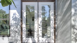 A modern house with a glass door leading to a covered porch.