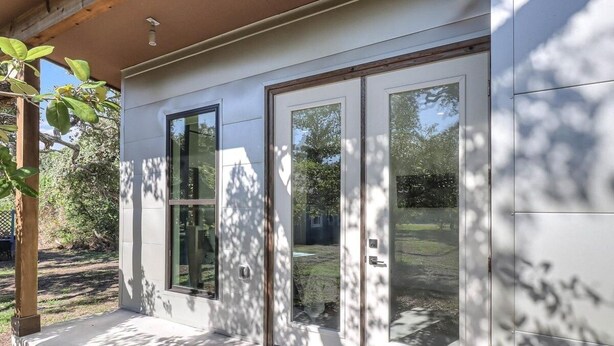 A modern building with large glass doors and a concrete porch.