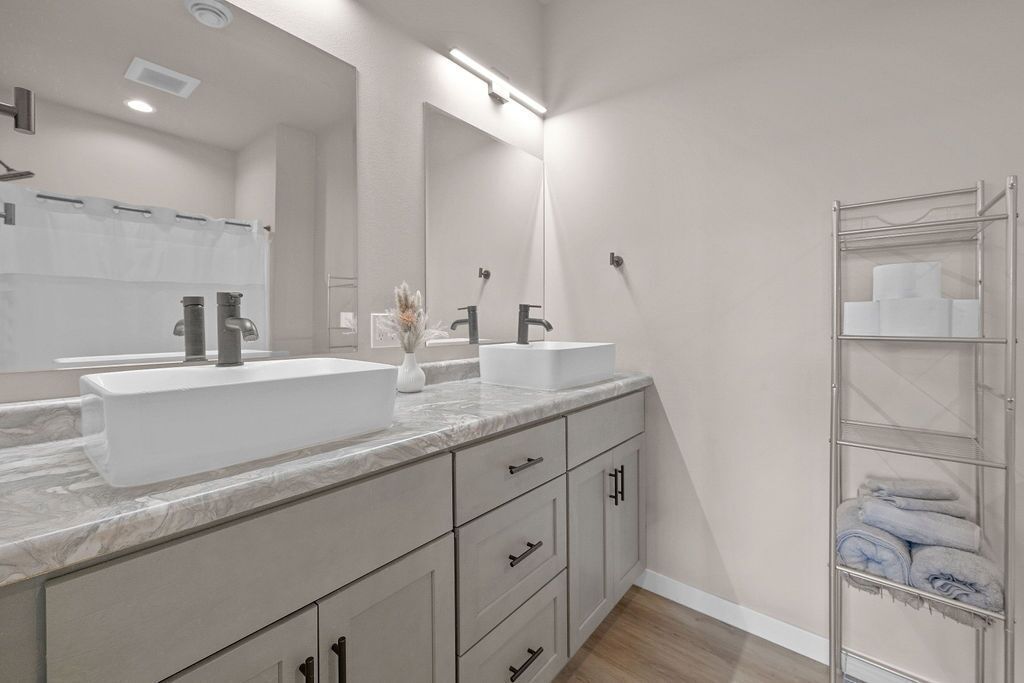 A modern bathroom with two sinks, a large mirror, and a towel rack.