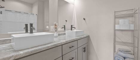 A modern bathroom with two sinks, a large mirror, and a towel rack.