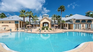 A large swimming pool surrounded by lounge chairs and palm trees, with a building in the background. - Luxury 5th floor oceanfront condo 754 at Cinnamon Beach! (Palm Coast)