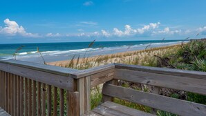 A wooden deck overlooking a beach with waves, sand, and sparse vegetation. - Luxury 5th floor oceanfront condo 754 at Cinnamon Beach! (Palm Coast)