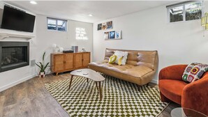 A living room with a sofa, a red chair, a coffee table, a fireplace, and a television.
