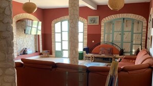 Ein geräumiges Wohnzimmer mit einer großen Couch, einer Hängematte und einem Essbereich mit Tisch und Stühlen.