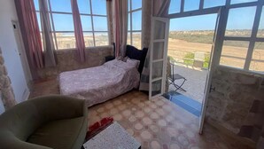 Ein Zimmer mit einem Bett, einem Sessel und Blick ins Freie.