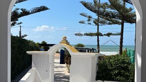 An arched entrance leading to a beach view with a tiled floor and a chair. - Étage RDC Villa vu sur mer (El Jadida)