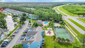 A residential area with a swimming pool, tennis court, and a road curving through the landscape. - 	Resort-Style 3BR Condo (Kissimmee)