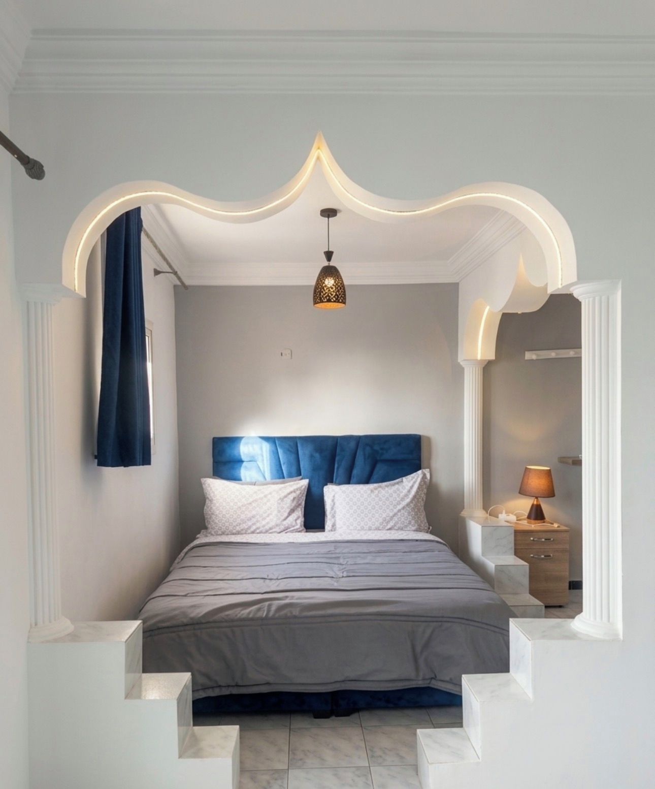Une chambre à coucher avec un lit, une table de chevet, une lampe et un luminaire au plafond.