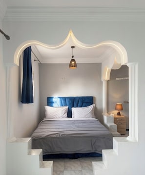 A bedroom with a bed, a nightstand, a lamp, and a ceiling light fixture.