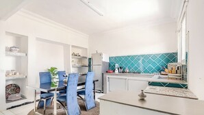 Eine moderne Küche mit Essbereich, weißen Schränken und einer türkisblauen Spritzschutzwand.