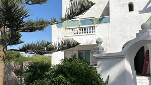 Ein weißes Gebäude mit Balkon, Steinbalustrade und einer kleinen Statue.