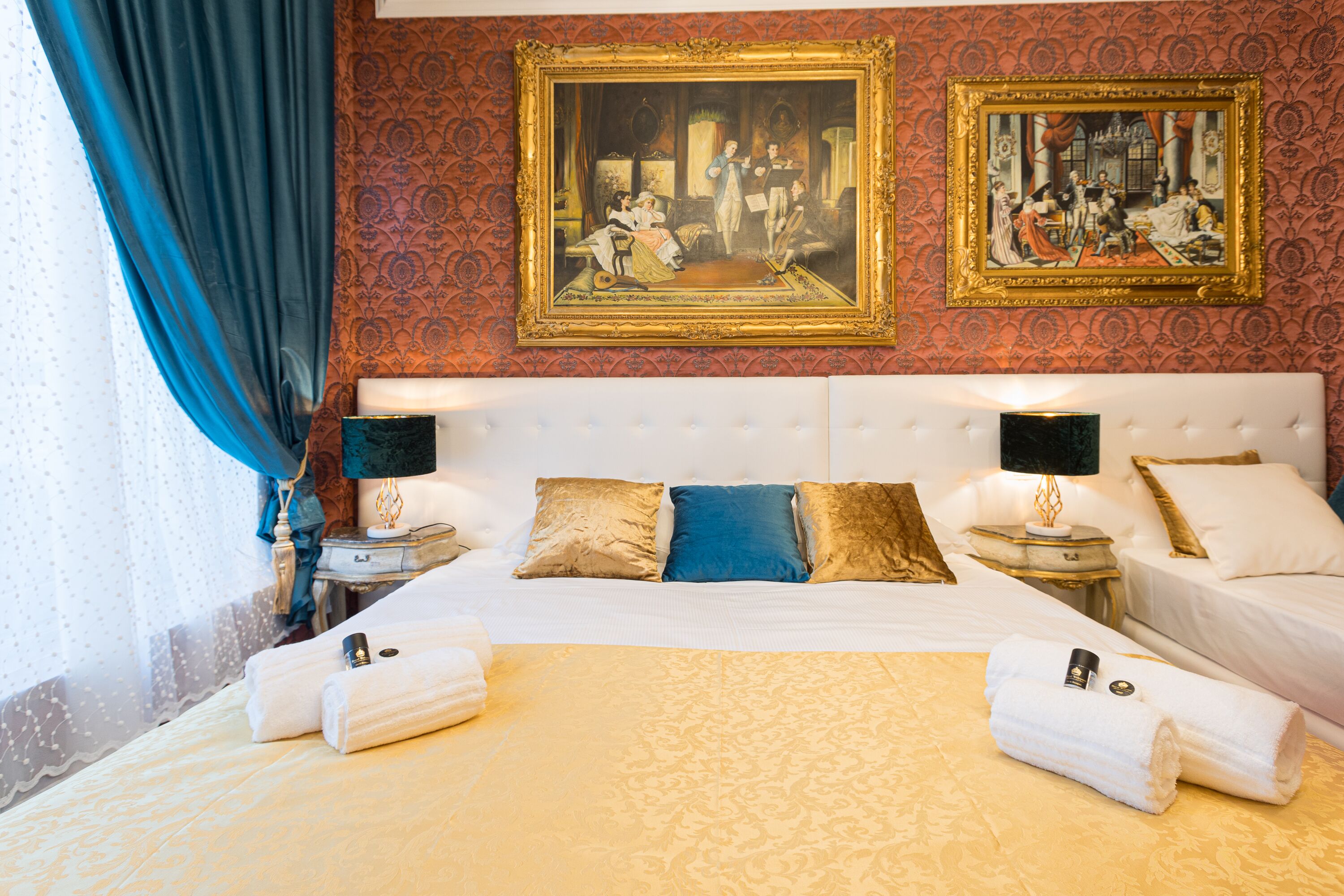 A hotel room with a large bed, two bedside tables, and two paintings on the wall.