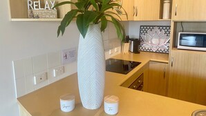 A modern kitchen with a large white vase, two small jars labeled 'Sugar' and 'Tea', and a decorative plant.