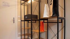 A room with a black metal shelving unit, a white door, and a wooden floor. - HOTEL AD Suites Nazionale (Rome)