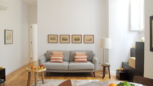 Una sala moderna con un sofá gris, una mesa de centro de madera y una mesita auxiliar.