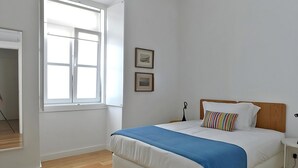 Une chambre à coucher avec un lit, une fenêtre et deux tableaux encadrés accrochés au mur.