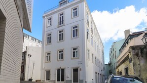 A multi-story building with a flat facade, multiple windows, and a door at the ground level. - Alfama Deluxe by Homing (Lisbon)