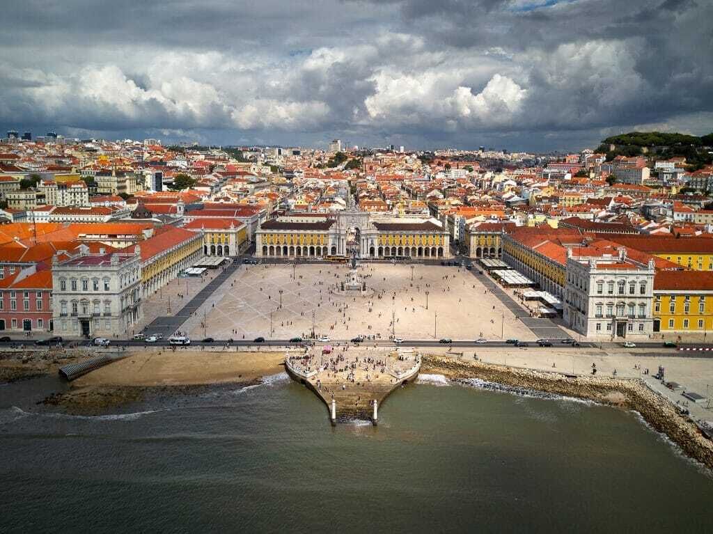 Vista aérea de una ciudad costera con una plaza destacada y un paseo marítimo.