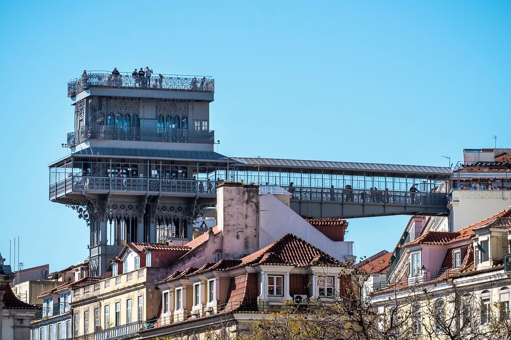 A historic building with a prominent tower and a pedestrian bridge.