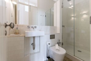 A modern bathroom with a glass-enclosed shower, a white sink, and a toilet. - Alfama Deluxe by Homing (Lisbon)