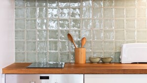 A kitchen with a stainless steel dishwasher, a wooden countertop, a white toaster, and a tiled backsplash. - Alfama Deluxe by Homing (Lisbon)