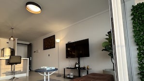 Un salon moderne avec un canapé en cuir marron, un téléviseur et un coin repas comprenant une table et des chaises.