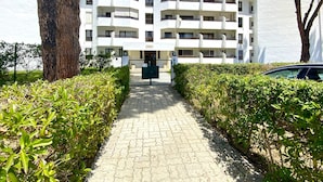 A multi-story residential building with a central entrance, surrounded by well-maintained hedges and a paved pathway leading to the entrance. - Vilamoura Charming With Pool by Homing (Loulé)