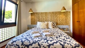 A bedroom with a large bed, two bedside tables, a wooden wardrobe, and a window with blinds. - Vilamoura Charming With Pool by Homing (Loulé)