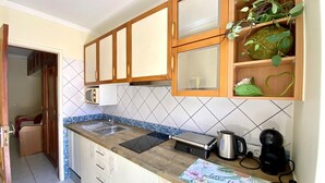 A kitchen with wooden cabinets, a tiled backsplash, a countertop with a coffee maker, and a toaster.