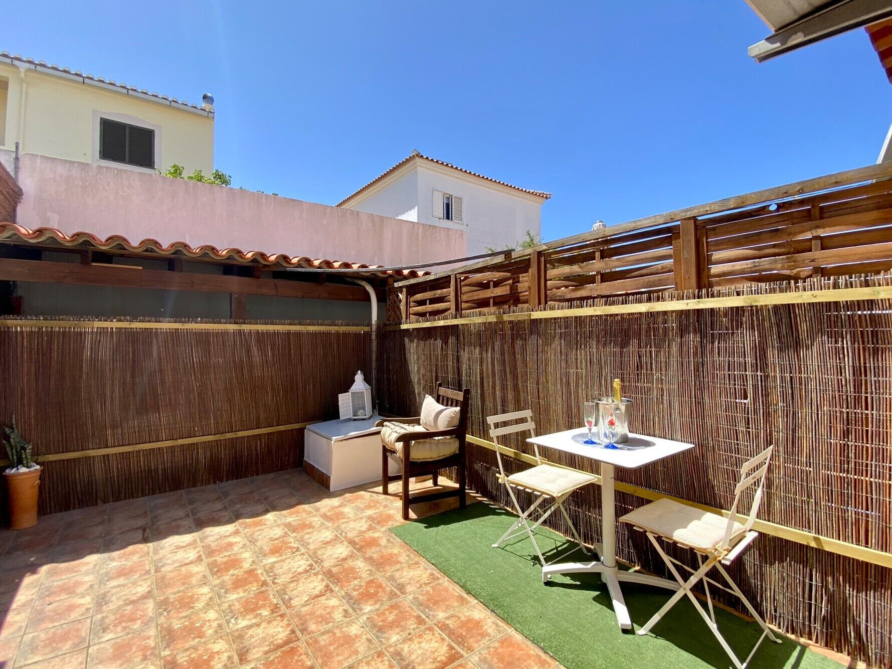 A patio area with a table and chairs, a small sofa, and a potted plant.