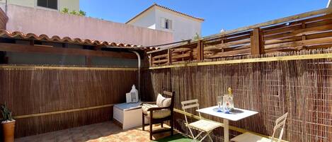 A patio area with a table and chairs, a small sofa, and a potted plant.