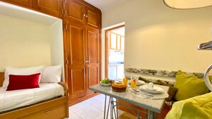A compact room with a bed, a kitchenette, and a dining area.