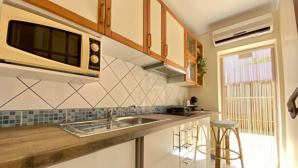 A kitchen with a microwave, stove, sink, and wooden cabinets.