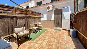 A patio with a tiled floor, a wooden table, and a cushioned bench.