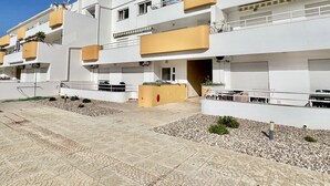 Un edificio residenziale moderno con diversi balconi, un cortile pavimentato e un cielo azzurro limpido.