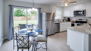 Una cocina moderna con comedor, electrodomésticos de acero inoxidable y vista al patio trasero.