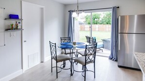 Una cocina moderna con una mesa de comedor, sillas y un refrigerador de acero inoxidable.