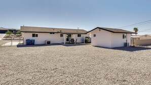 A single-story house with a gravel driveway, a front porch with chairs, and a small patio area. - Patio + Private Casita: Lake Havasu City Home! (Lake Havasu City)