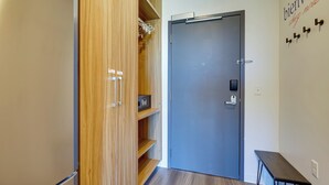 Um corredor com um armário de madeira, uma porta azul e um banco.